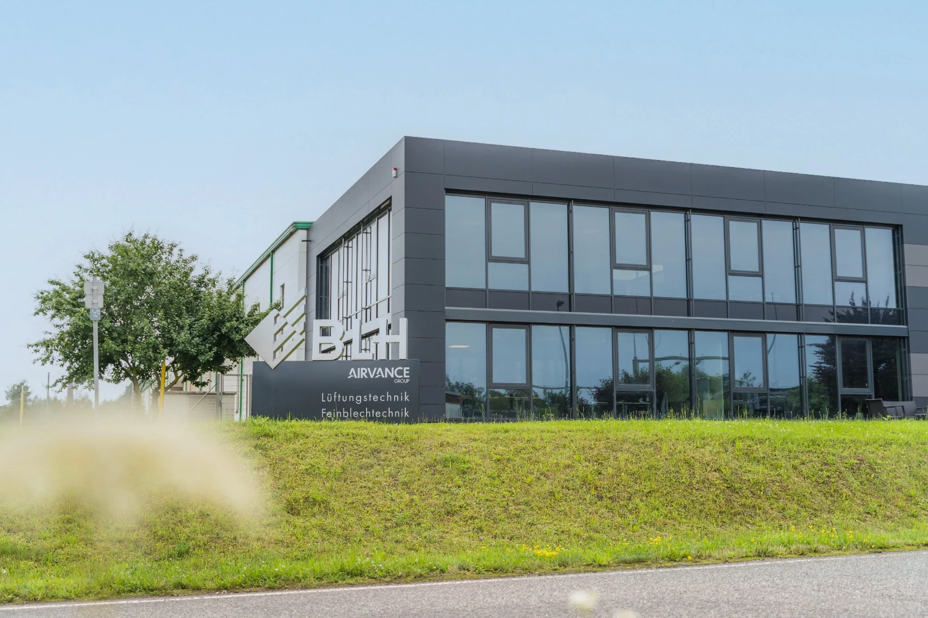 Verwaltungsgebäude der BLH in Trier mit Firmenschild und Wiese im Vordergrund